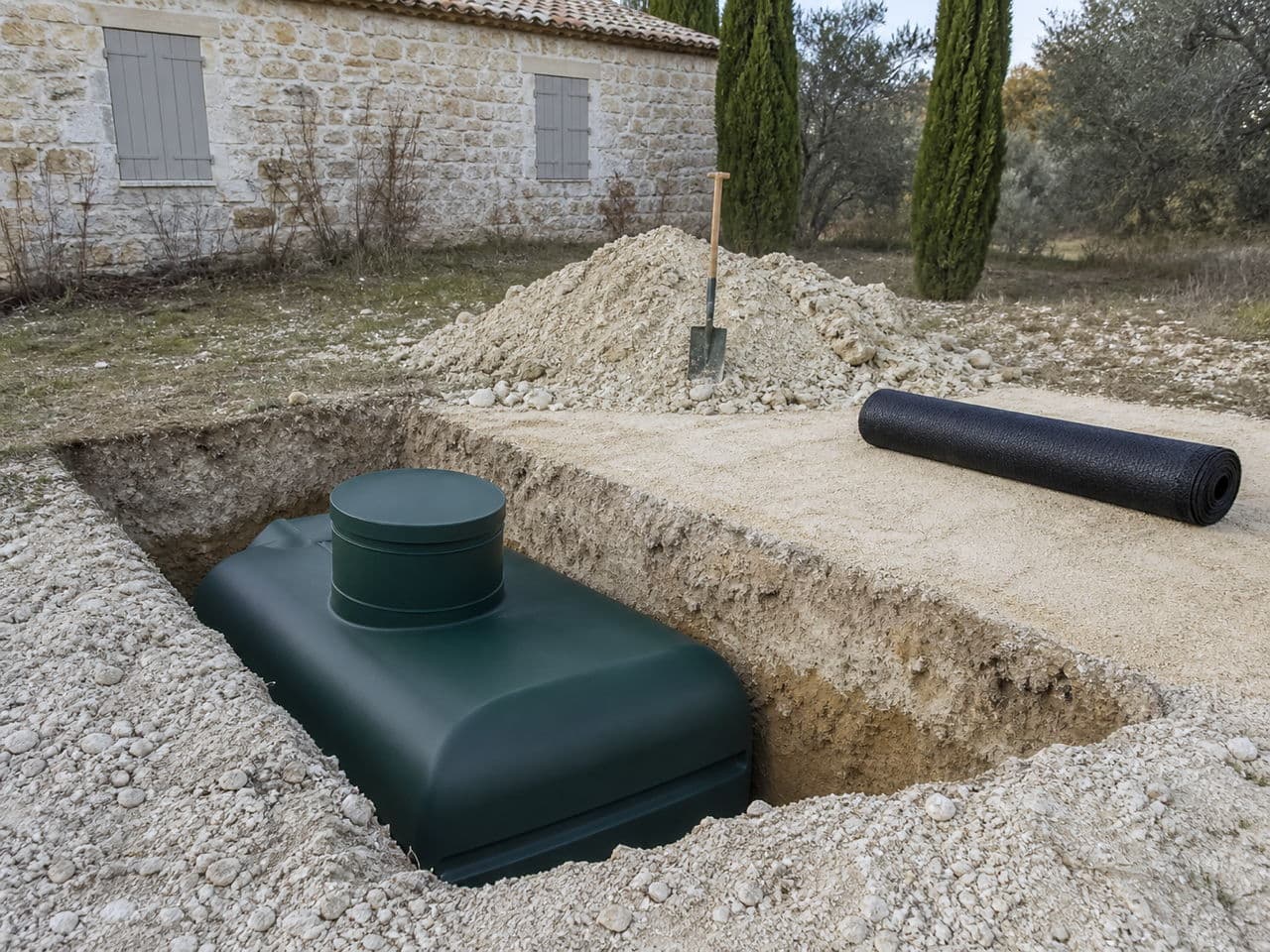 Chantier d'assainissement non collectif avec mini-pelle, lit de sable et cuve de fosse toutes eaux