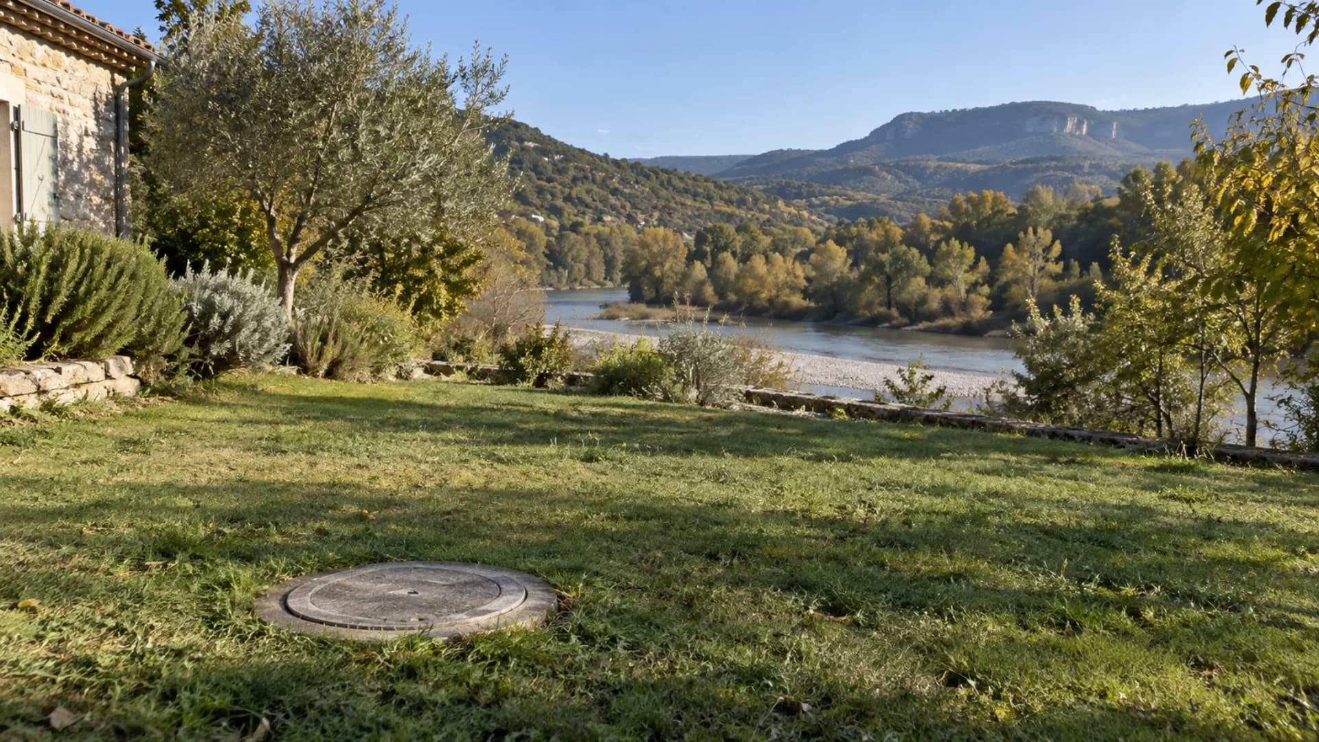 Regard d'assainissement fermé dans un jardin enherbé près d'une rivière, sur un terrain non submergé