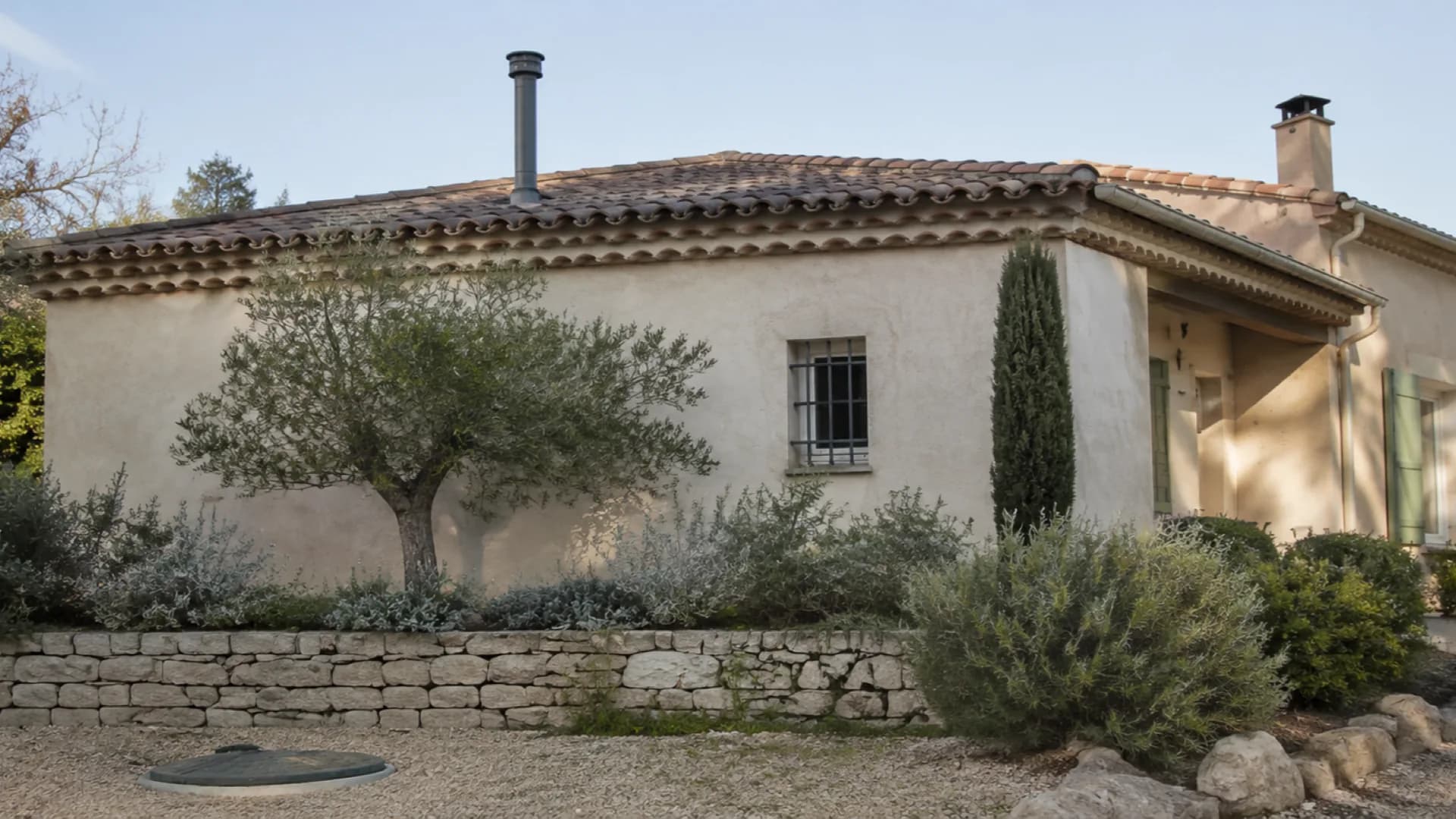 Évent de fosse toutes eaux sur le toit d'une maison provençale et regard fermé dans le jardin