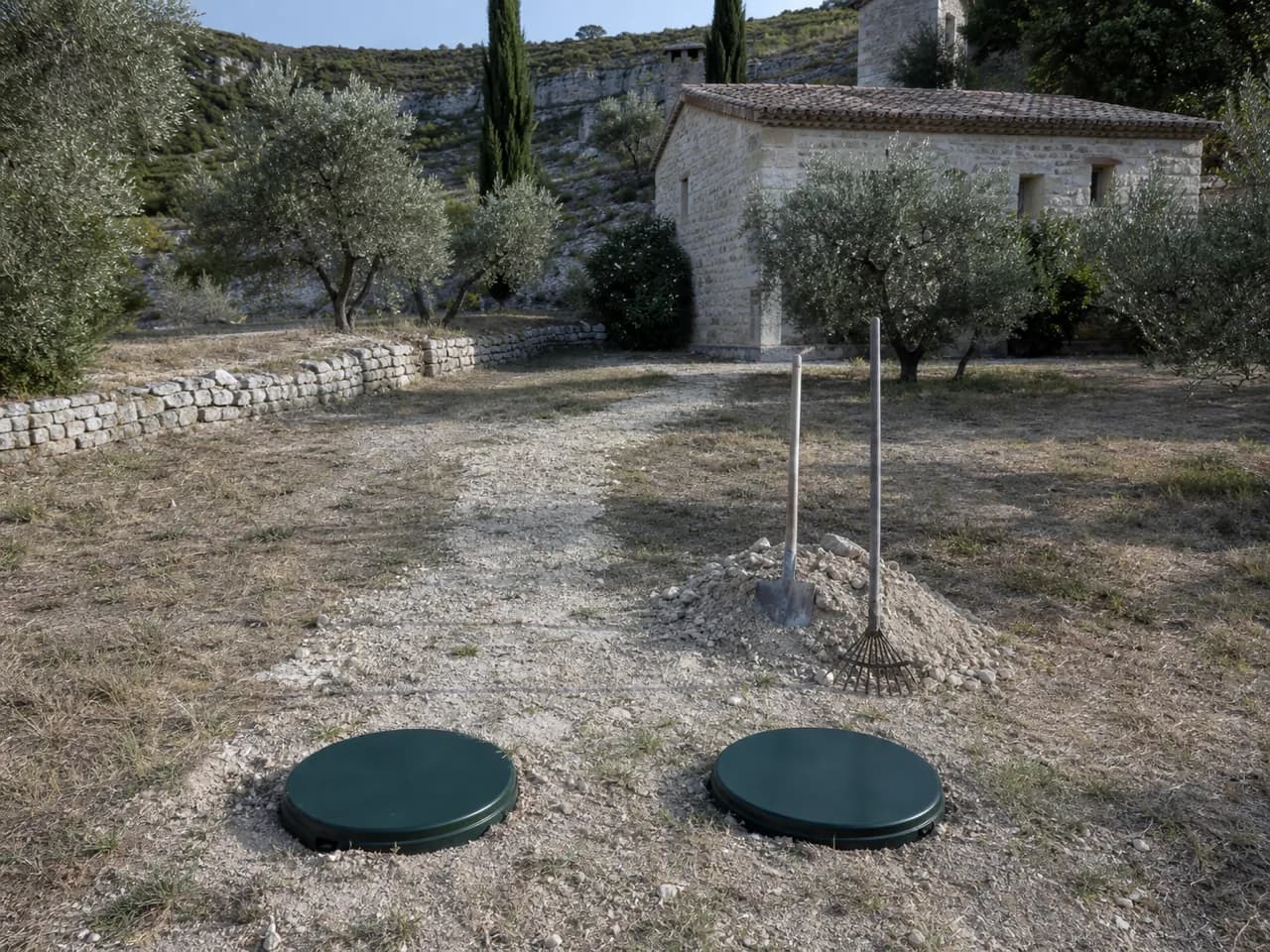 Tranchée refermée dans le jardin d'un mas, deux tampons de regard affleurant la pelouse