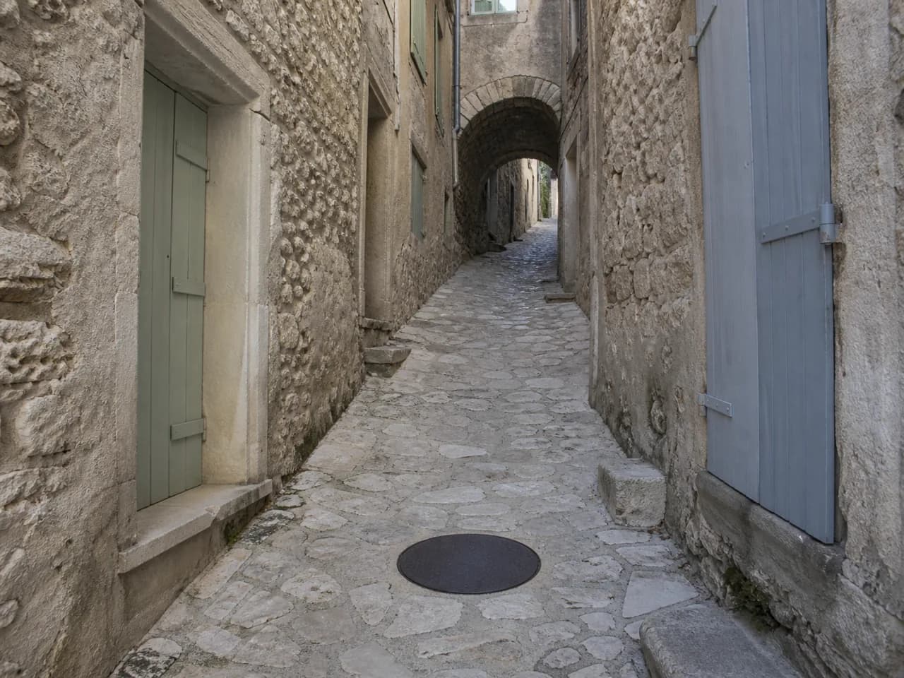Ruelle pavée du centre ancien de Nyons, tampon de regard en fonte dans le pavage
